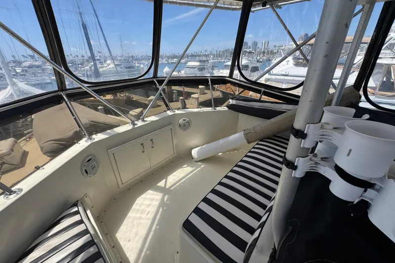 Interior view of 1985 Hatteras 45 Convertible yacht with striped seating and marina backdrop.