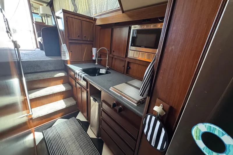Interior of 1985 Hatteras 45 Convertible yacht kitchen with wood cabinetry and modern appliances.