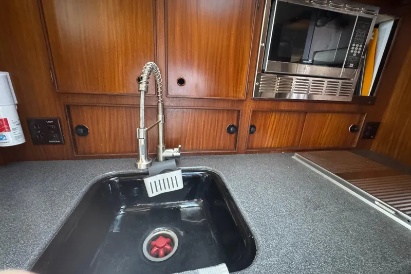 1985 Hatteras 45 Convertible yacht kitchen with sink, faucet, and microwave.