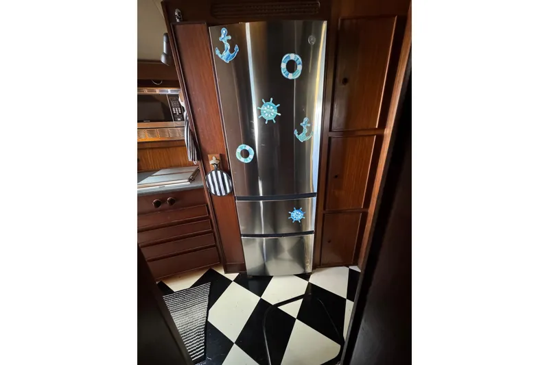 Nautical-themed kitchen in 1985 Hatteras 45 Convertible yacht with stainless steel fridge.