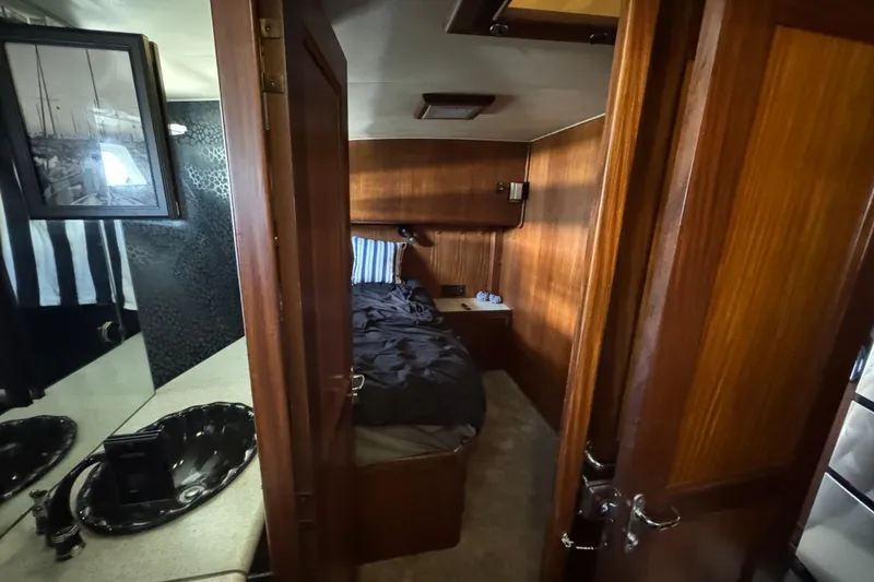 Interior of 1985 Hatteras 45 Convertible yacht, featuring cozy wood-paneled cabin and bathroom.