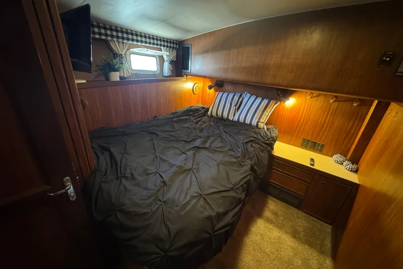 Cozy cabin interior of 1985 Hatteras 45 Convertible yacht with bed and window.