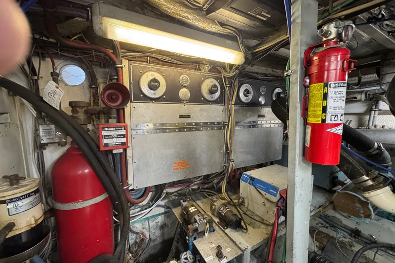 Engine room of a 1985 Hatteras 45 Convertible yacht with control panels and fire extinguishers.