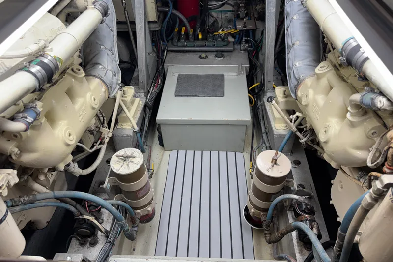 Engine room of a 1985 Hatteras 45 Convertible yacht, showcasing dual engines and mechanical components.