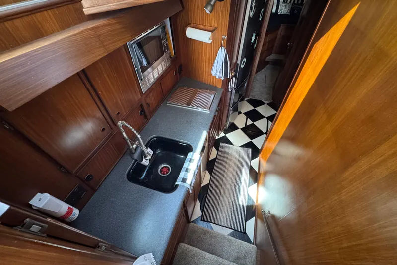 Interior of 1985 Hatteras 45 Convertible yacht kitchen with wood cabinetry and checkered floor.