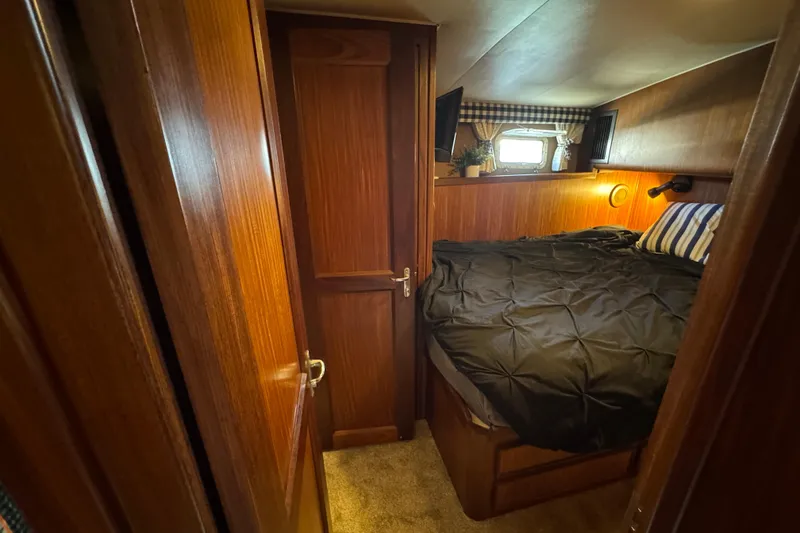Cozy cabin interior of 1985 Hatteras 45 Convertible yacht with wood paneling and bed.