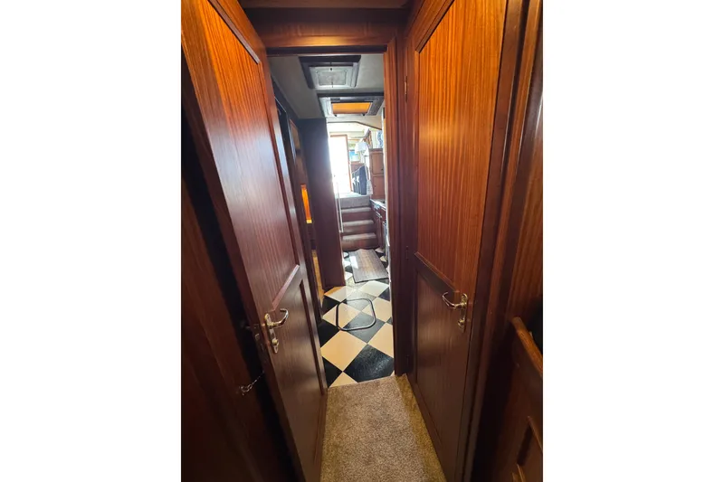 Interior hallway of 1985 Hatteras 45 Convertible yacht with wood paneling and checkered flooring.