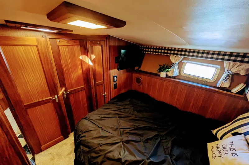 Cozy cabin interior of 1985 Hatteras 45 Convertible yacht with wood paneling and window.