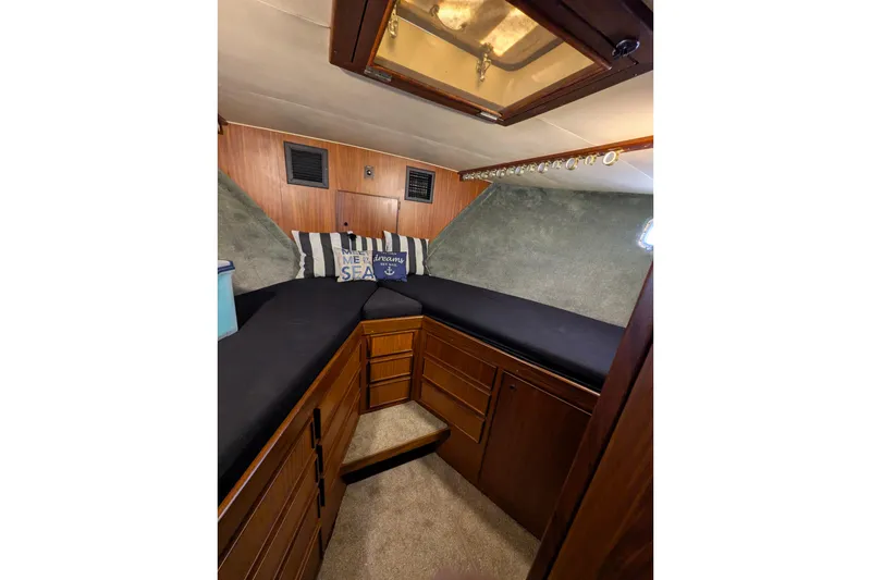 Interior cabin of 1985 Hatteras 45 Convertible yacht with cozy bedding and wooden cabinetry.