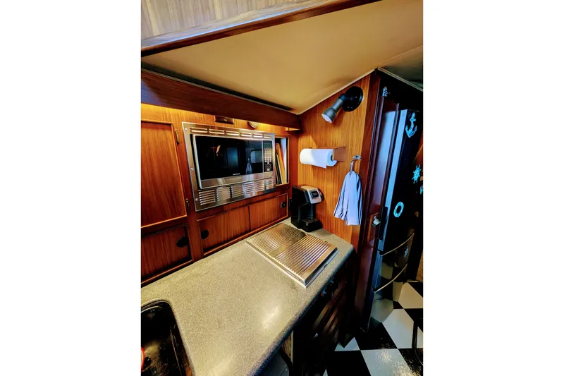 1985 Hatteras 45 Convertible yacht kitchen with microwave, coffee maker, and wooden cabinetry.