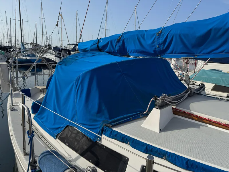 1990 Catalina 30 MkII sailboat with blue covers docked in a marina.