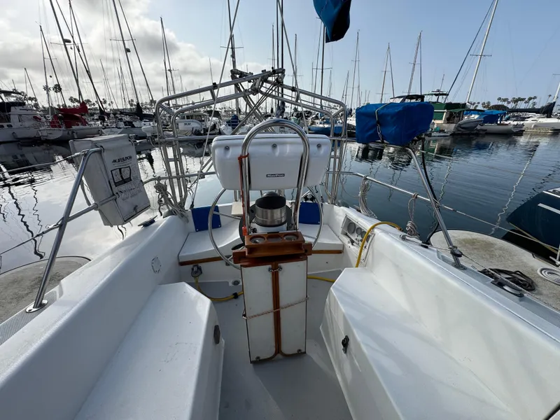 1990 Catalina 30 MkII sailboat cockpit view in marina, surrounded by docked boats.