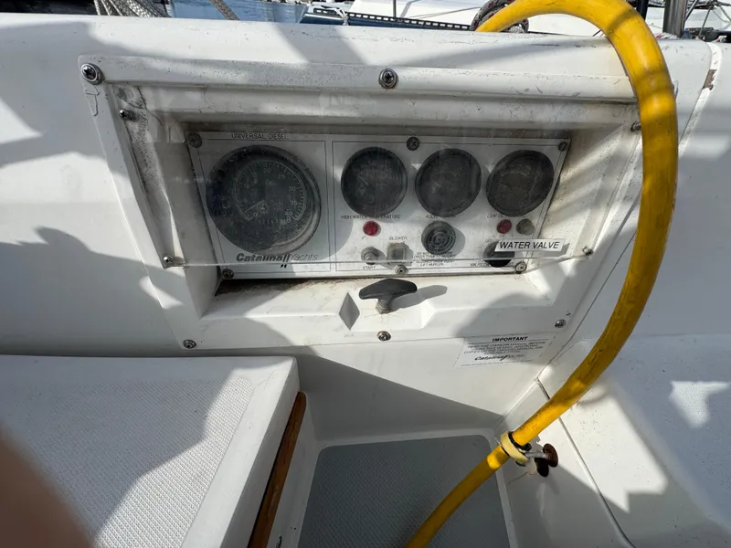Control panel of a 1990 Catalina 30 MkII sailboat with gauges and a yellow hose.