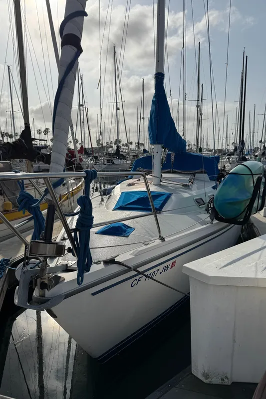 1990 Catalina 30 MkII sailboat docked in a marina, featuring blue sail covers.