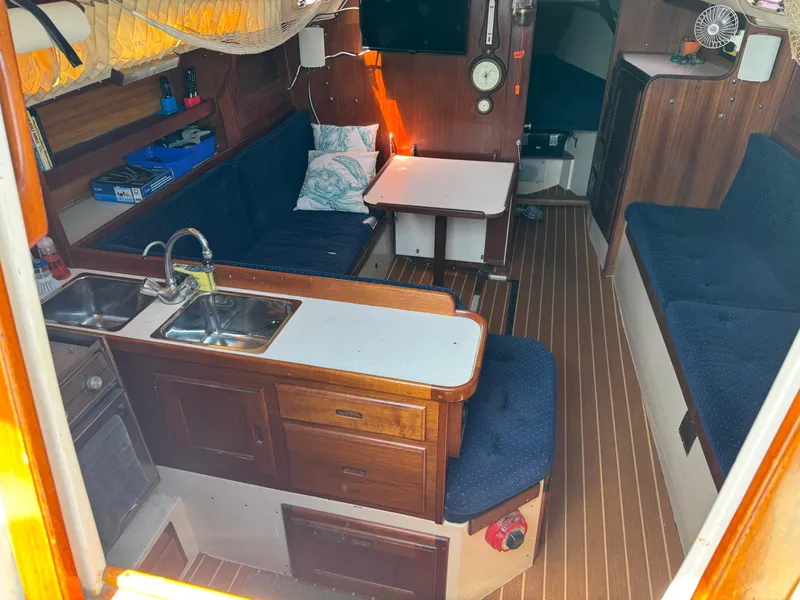 Interior of a 1990 Catalina 30 MkII sailboat with cozy seating and compact kitchen.