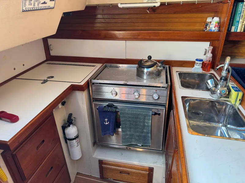 1990 Catalina 30 MkII yacht kitchen with stove, sink, and wooden cabinetry.