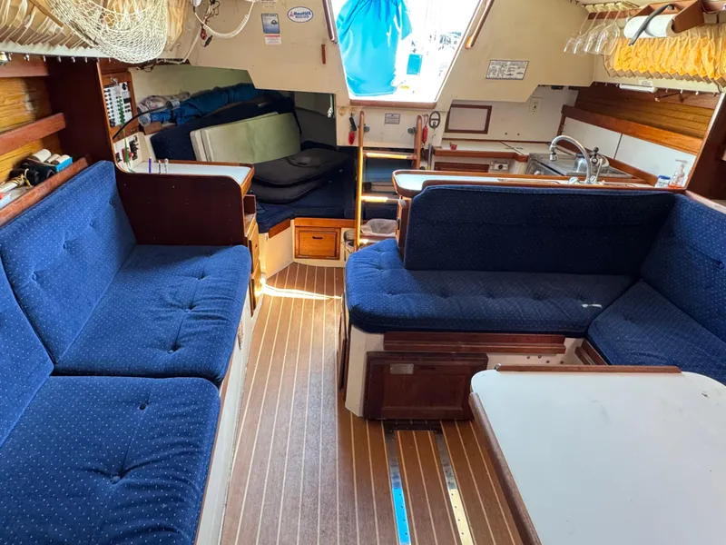 Interior of a 1990 Catalina 30 MkII sailboat with blue cushioned seating and wooden flooring.