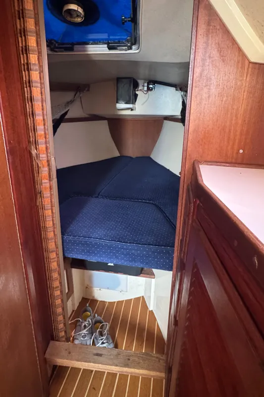 Cozy cabin interior of 1990 Catalina 30 MkII sailboat with blue cushions and wooden accents.