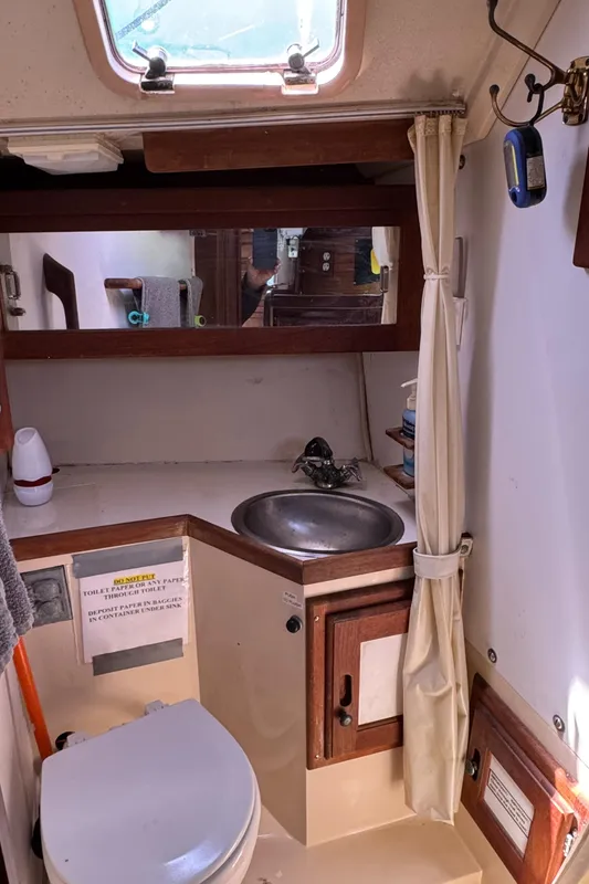 1990 Catalina 30 MkII yacht bathroom with sink, toilet, mirror, and storage.