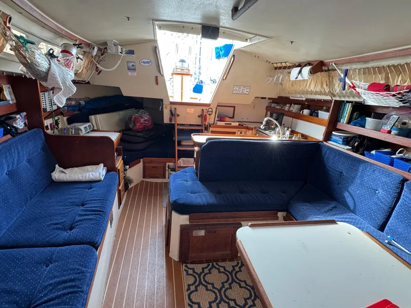 Interior of a 1990 Catalina 30 MkII sailboat with blue seating and wooden accents.
