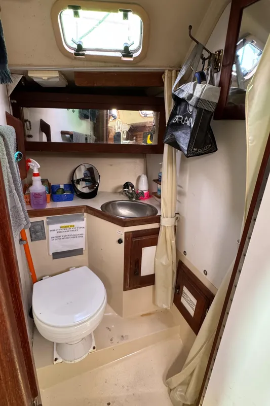 Compact bathroom in a 1990 Catalina 30 MkII sailboat with sink, toilet, and storage.