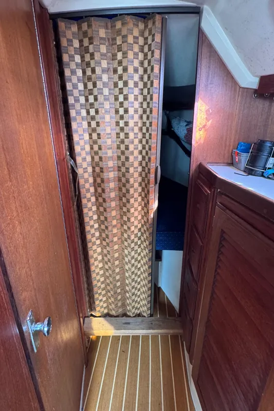 1990 Catalina 30 MkII interior with wooden cabinetry and checkered curtain.