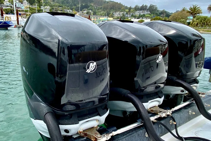 Triple Mercury outboard engines on a 2006 Donzi 38 ZSF boat, docked in a scenic marina.