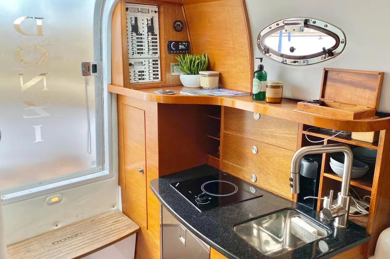 Luxurious 2006 Donzi 38 ZSF yacht interior with modern kitchenette and wooden cabinetry.