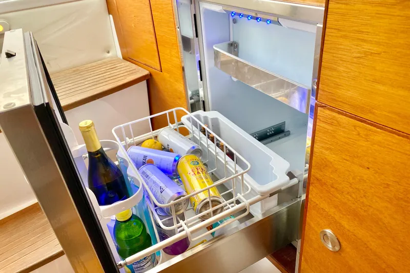 Open fridge on 2006 Donzi 38 ZSF boat, stocked with beverages and snacks.
