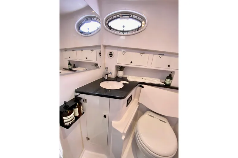 Luxurious bathroom interior of 2006 Donzi 38 ZSF boat with modern fixtures and porthole windows.