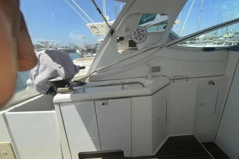 2006 Cruisers Yachts 370 Express cockpit with sink and covered equipment, docked at marina.