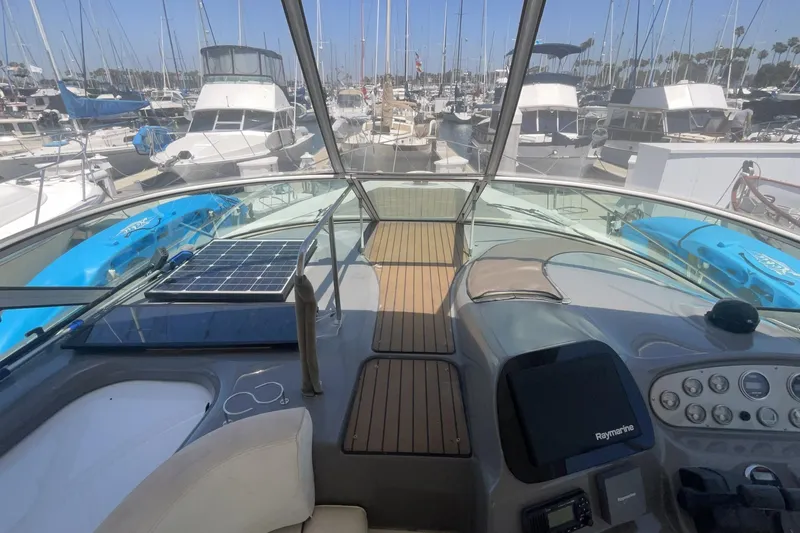 2006 Cruisers Yachts 370 Express cockpit view with marina backdrop, featuring solar panel and kayaks.