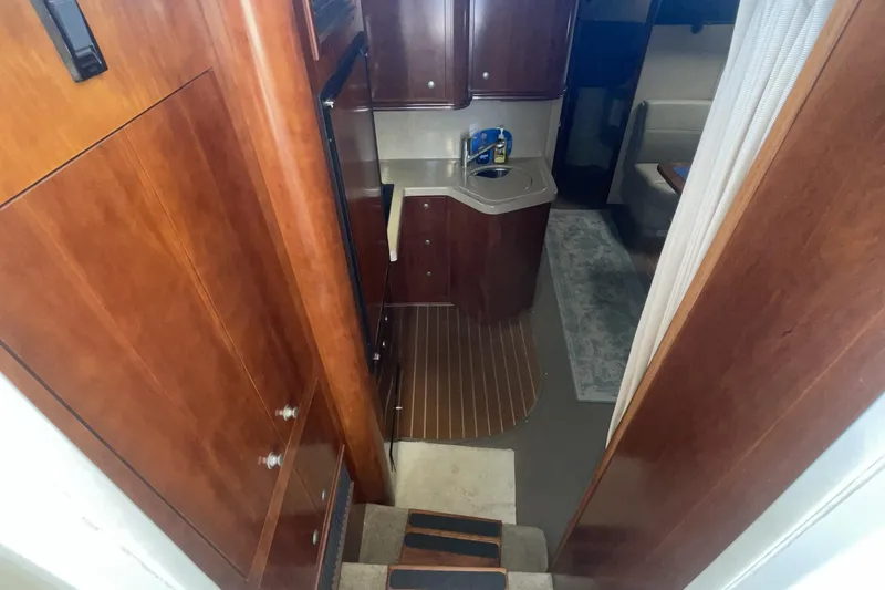Interior view of 2006 Cruisers Yachts 370 Express, featuring wooden cabinetry and compact kitchenette.