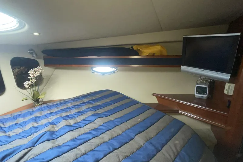 Cozy cabin interior of 2006 Cruisers Yachts 370 Express with striped bedding and TV.