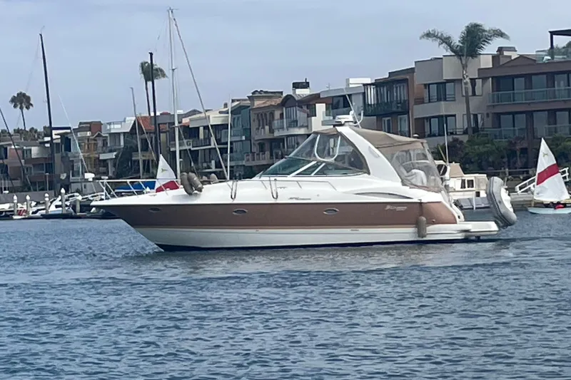 2006 Cruisers Yachts 370 Express in marina, surrounded by modern waterfront buildings.