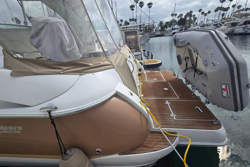 2006 Cruisers Yachts 370 Express docked with inflatable boat, wooden deck, and marina view.