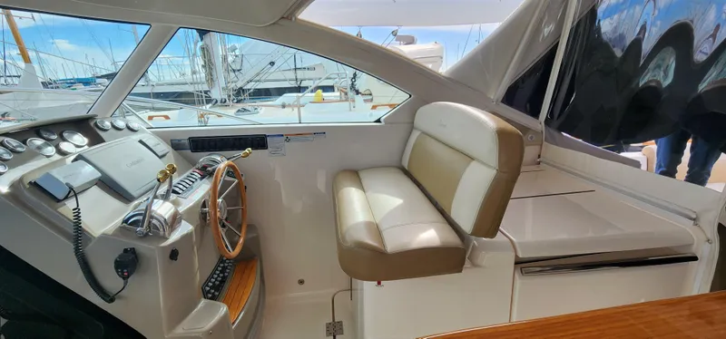 2012 Tiara Yachts 3100 Coronet helm with beige seating and wooden steering wheel.