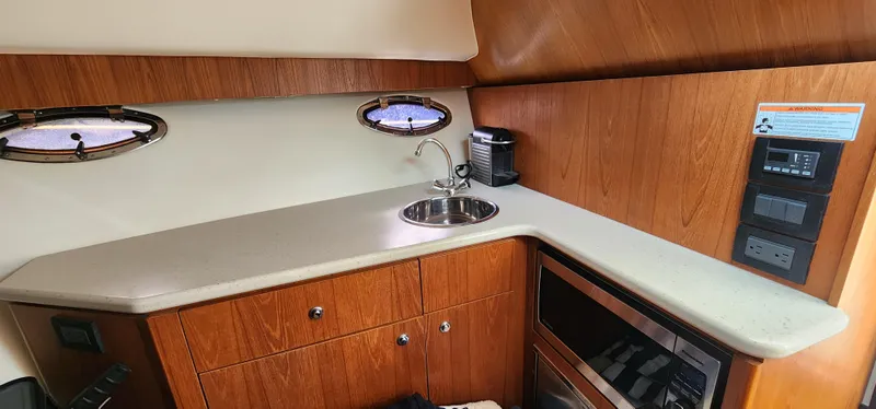 2012 Tiara Yachts 3100 Coronet interior with kitchenette, sink, and wooden cabinetry.