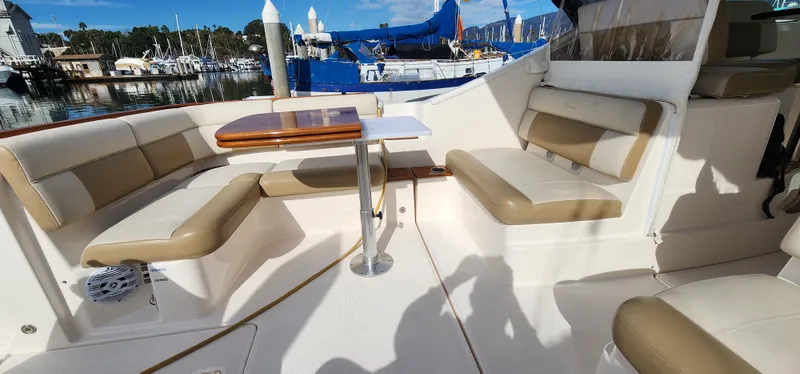 2012 Tiara Yachts 3100 Coronet interior with beige seating and table, docked at marina.