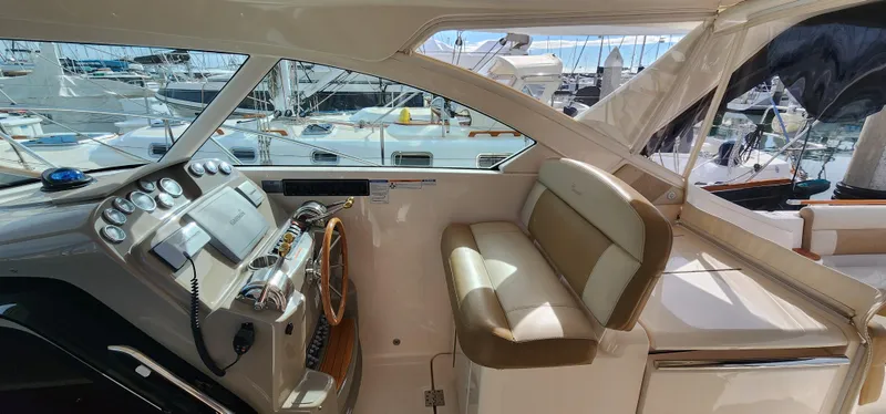 2012 Tiara Yachts 3100 Coronet cockpit with steering wheel, controls, and seating, docked at marina.