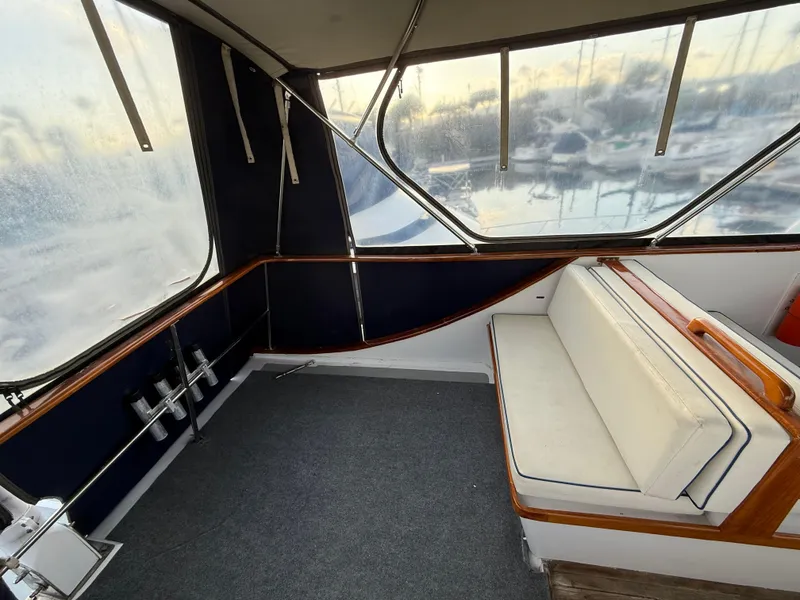 Interior of a 1978 C & L 37 boat with cushioned seating and large windows.