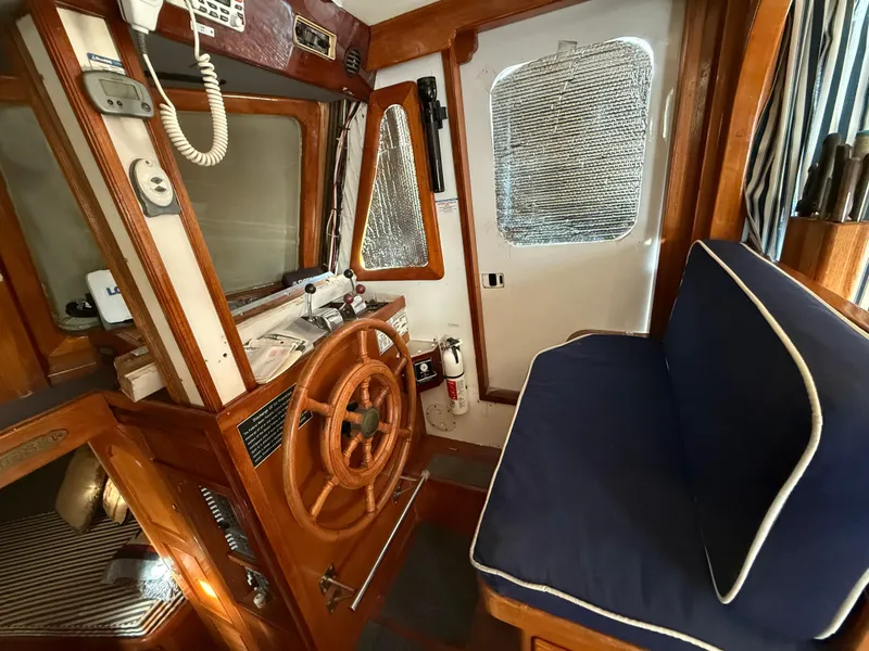 Interior of a 1978 C & L 37 boat with wooden helm and blue seating.