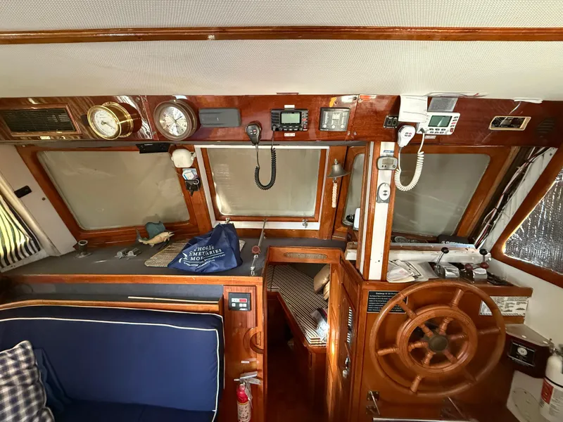1978 C & L 37 boat interior with wooden helm, navigation instruments, and blue seating.