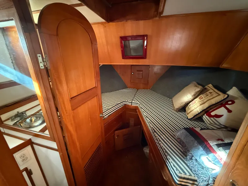 Cozy cabin interior of a 1978 C & L 37 boat with striped bedding and wooden finishes.