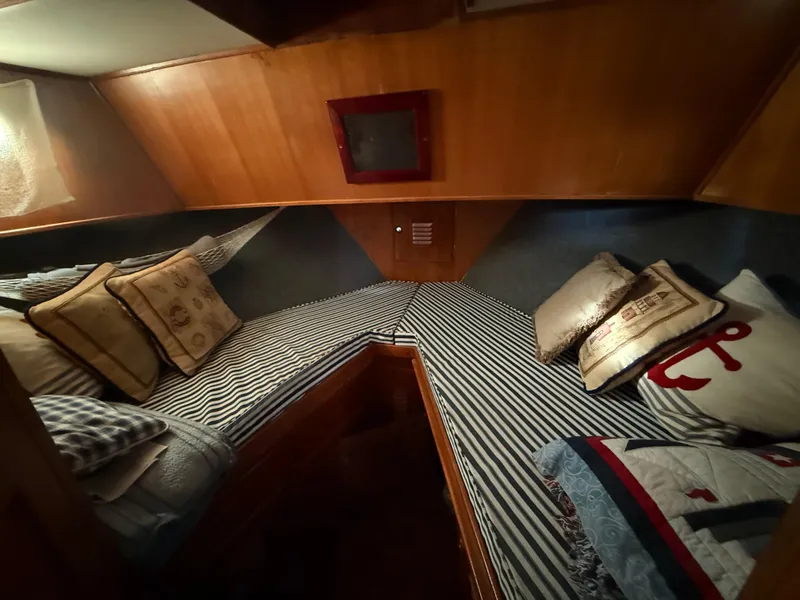 Cozy cabin interior of 1978 C & L 37 boat with striped bedding and nautical-themed pillows.