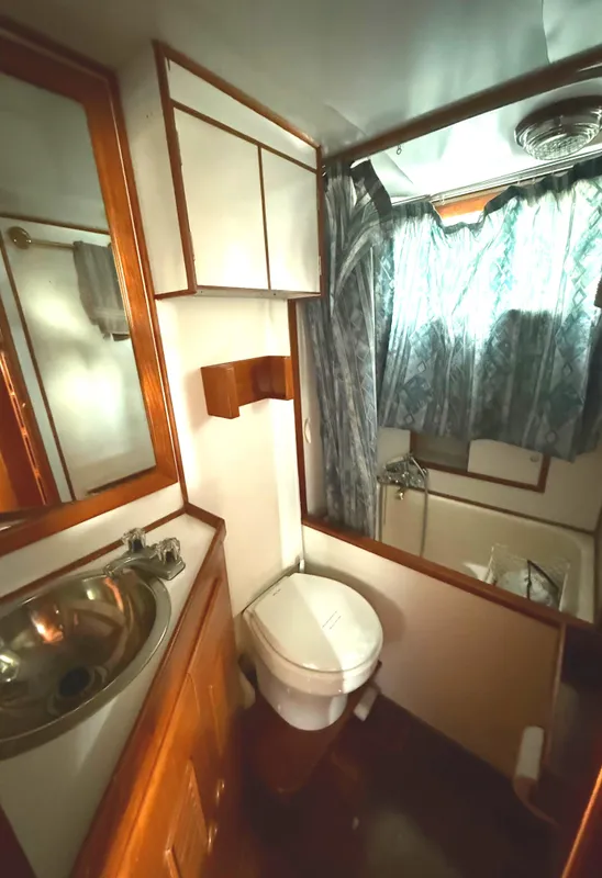1978 C & L 37 yacht bathroom with sink, toilet, and shower curtain.