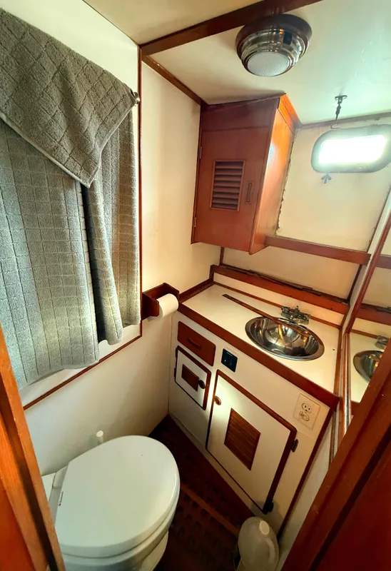1978 C & L 37 boat bathroom with sink, toilet, and wooden cabinetry.