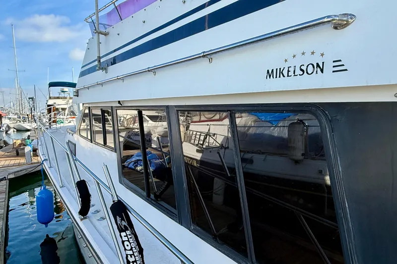1990 Mikelson 42 yacht docked at marina, showcasing sleek design and reflective windows.