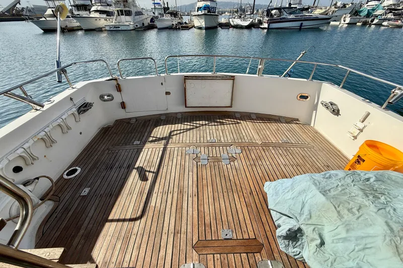 Deck of 1990 Mikelson 42 yacht with wooden flooring, docked at marina.