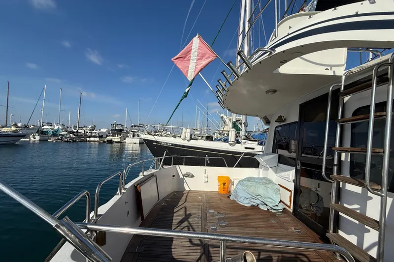 1990 Mikelson 42 yacht docked at marina, featuring spacious deck and clear blue sky.